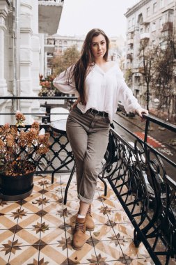Balkonda beyaz gömlekli güzel bir kızın fotoğrafı.