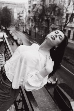 Balkonda beyaz gömlekli güzel bir kızın fotoğrafı.