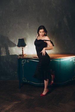 Siyah elbiseli güzel bir kızın fotoğraf stüdyosunda fotoğraf çekimi.