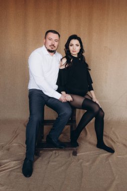 Siyah bir beden ve tayt içinde kumaş arka planı olan bir fotoğraf stüdyosunda hamilelik fotoğrafı çekimi.