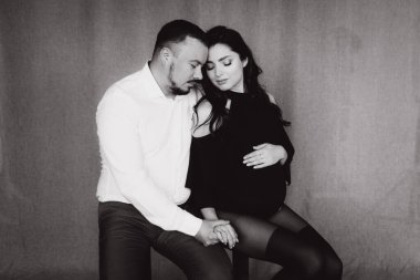 Siyah bir beden ve tayt içinde kumaş arka planı olan bir fotoğraf stüdyosunda hamilelik fotoğrafı çekimi.