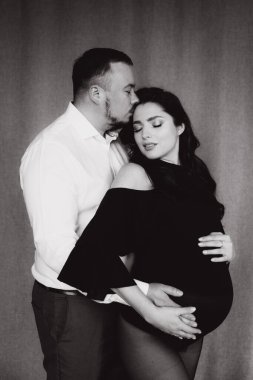 Siyah bir beden ve tayt içinde kumaş arka planı olan bir fotoğraf stüdyosunda hamilelik fotoğrafı çekimi.