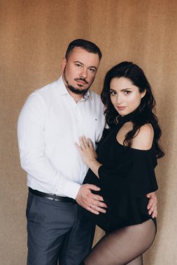 Siyah bir beden ve tayt içinde kumaş arka planı olan bir fotoğraf stüdyosunda hamilelik fotoğrafı çekimi.