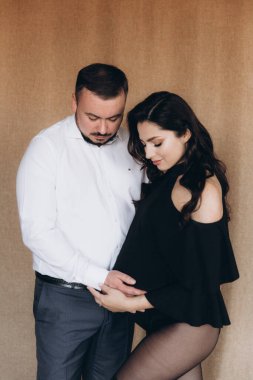 Siyah bir beden ve tayt içinde kumaş arka planı olan bir fotoğraf stüdyosunda hamilelik fotoğrafı çekimi.