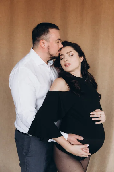 Siyah bir beden ve tayt içinde kumaş arka planı olan bir fotoğraf stüdyosunda hamilelik fotoğrafı çekimi.