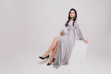 Güzel bir çiftin hamilelik fotoğrafı. Gri elbiseli ve takım elbiseli müstakbel ebeveynler.