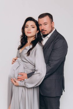 Güzel bir çiftin hamilelik fotoğrafı. Gri elbiseli ve takım elbiseli müstakbel ebeveynler.