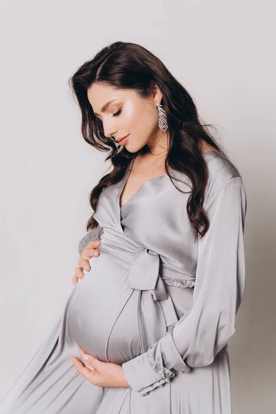 Güzel bir çiftin hamilelik fotoğrafı. Gri elbiseli ve takım elbiseli müstakbel ebeveynler.