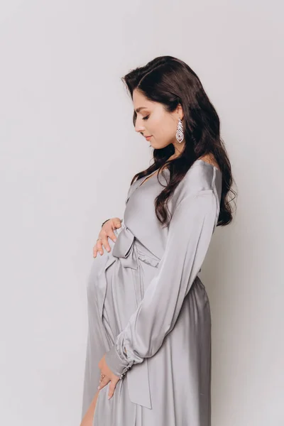 Güzel bir çiftin hamilelik fotoğrafı. Gri elbiseli ve takım elbiseli müstakbel ebeveynler.