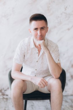 Şık bir adam, model, şık şortlu ve atölyede bir gömlek, yaz modası.