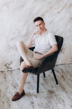 Şık bir adam, model, şık şortlu ve atölyede bir gömlek, yaz modası.