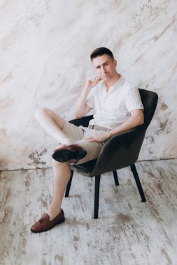 Şık bir adam, model, şık şortlu ve atölyede bir gömlek, yaz modası.