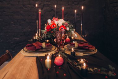 Siyah dekorlu şölen masası, mumlar, pasta ve çiçekler, marsal ve garnet, altın çatal bıçak takımı.