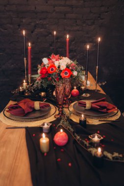 Siyah dekorlu şölen masası, mumlar, pasta ve çiçekler, marsal ve garnet, altın çatal bıçak takımı.