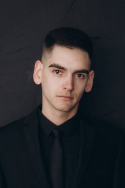 Siyah elbiseli güzel bir çiftin düğünü, Marsala renginde bir buket, mumlarla dolu bir şenlik masasında ve siyah bir duvara yaslanmış bir pasta.