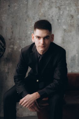 Siyah elbiseli güzel bir çiftin düğünü, Marsala renginde bir buket, mumlarla dolu bir şenlik masasında ve siyah bir duvara yaslanmış bir pasta.