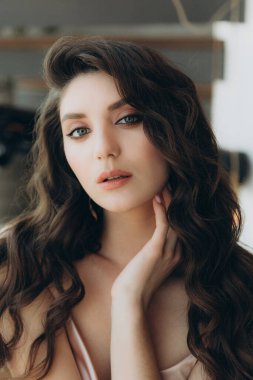 Güzel, şık ve zarif kız esmer, model, makyaj ve şeftali rengi ipek elbise içinde kıvırcık saçlı moda tarzında bir dergi fotoshoot için..