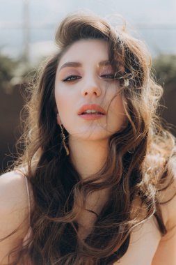 Güzel, şık ve zarif kız esmer, model, makyaj ve şeftali rengi ipek elbise içinde kıvırcık saçlı moda tarzında bir dergi fotoshoot için..