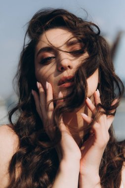 Güzel, şık ve zarif kız esmer, model, makyaj ve şeftali rengi ipek elbise içinde kıvırcık saçlı moda tarzında bir dergi fotoshoot için..