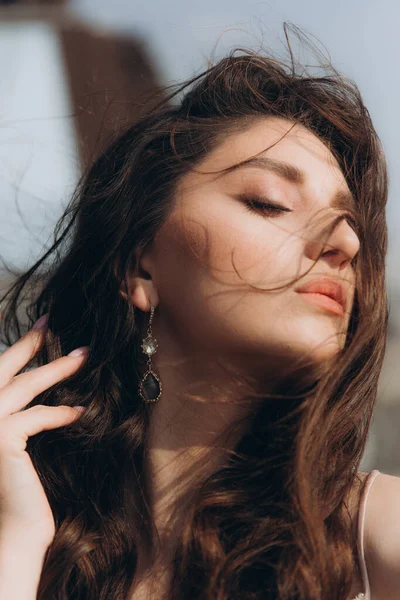 Güzel, şık ve zarif kız esmer, model, makyaj ve şeftali rengi ipek elbise içinde kıvırcık saçlı moda tarzında bir dergi fotoshoot için..