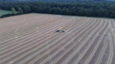 Weiterstadt yakınlarındaki saman balyaları, traktör ve treylerle hasat edilmiş alan, Hesse, insansız hava aracı videosu.