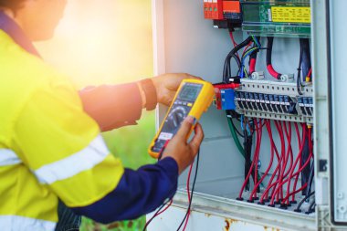 İşçiler, normal çalışan sistemlere doğrulama için güneş enerjisinden üretilen elektrik kablolarının voltajını ölçmek için Multimetre kullanıyorlar.
