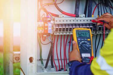 İşçiler, normal çalışan sistemlere doğrulama için güneş enerjisinden üretilen elektrik kablolarının voltajını ölçmek için Multimetre kullanıyorlar.