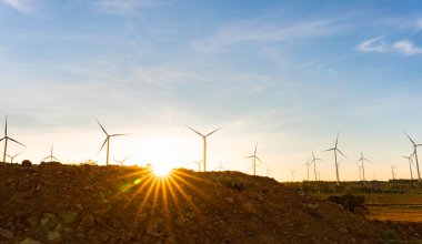 Rüzgar türbinleri alternatif bir elektrik kaynağıdır, sürdürülebilir kaynaklar kavramı, rüzgar jeneratörleri arka planda türbinleri, yenilenebilir enerji kavramı ile yaz aylarında güzel turuncu güneş ışığı.