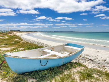 Güzel mavi gökyüzünün altında, Güney Afrika 'da bir sahilde küçük bir sandal.