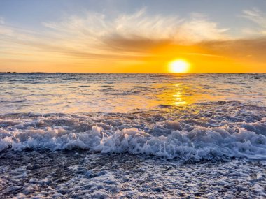 Huzurlu sahilde dramatik Altın Gün batımı dalgalar çakıl taşı kıyılarını kırbaçlıyor, Güney Afrika