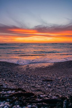 Huzurlu sahilde dramatik Altın Gün batımı dalgalar çakıl taşı kıyılarını kırbaçlıyor, Güney Afrika