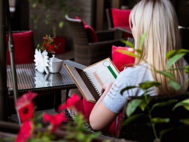 Kafede oturan sarışın bir kızın menüsü.