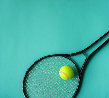 Tenis raketi, tenis topu yeşil arka planda uzanır, spor minimalizmi, üst manzara