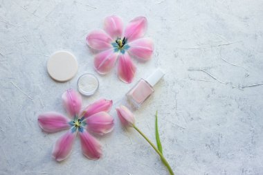 Oje sertleştirme, sünger, laleler ve arka planda kozmetik minimalizmi üzerine bir kavanoz toz standı.