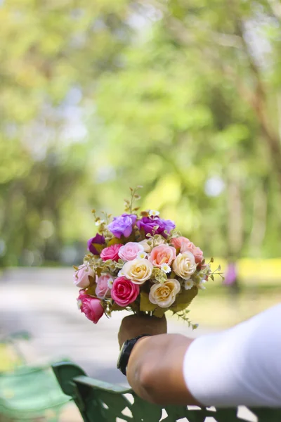 Stock Buquê de fotos de flores e sentado em um banco em um parque — Fotografia de Stock