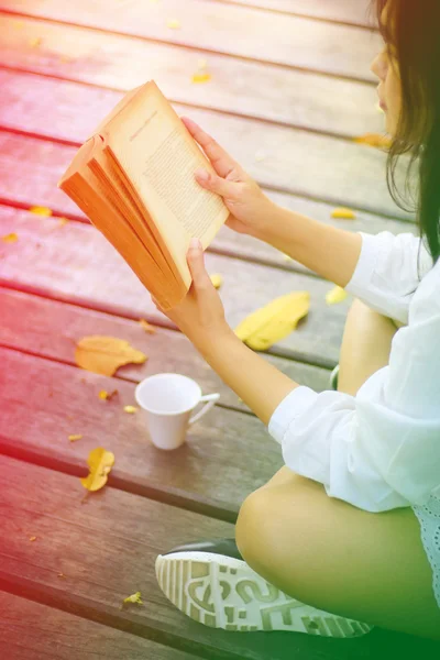 Cute young woman sitting on the park and reading the book soft f — Stock Photo, Image