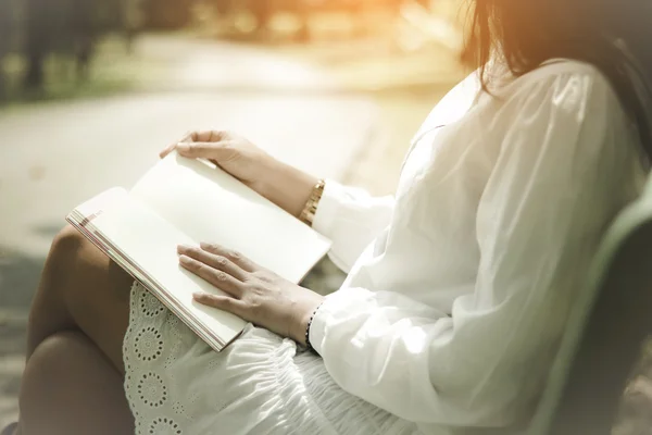 Stock Photo Young woman sitting in a park and reading a book soft focus vintage style — Stock Photo, Image