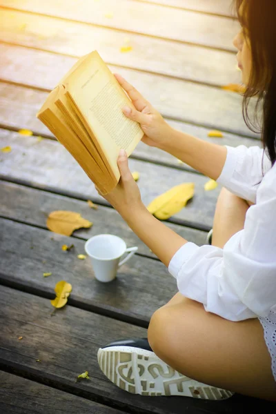 Sevimli genç kadın parkta üzerinde oturan ve kitap yumuşak f okuma — Stok fotoğraf