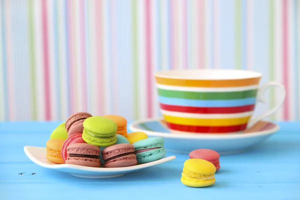 Stock Photo Quelques macarons et une tasse rose sur une table en bois blanc — Photo