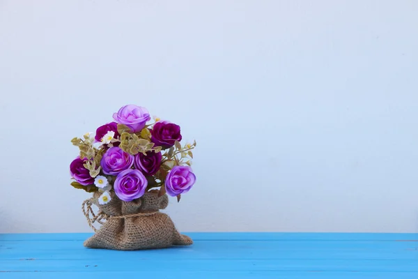 Пластиковый цветочный букет из различных цветов на синем столе — стоковое фото