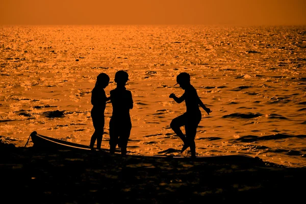 Silhouette von Kindern, die am Strand spielen und spazieren gehen — Stockfoto