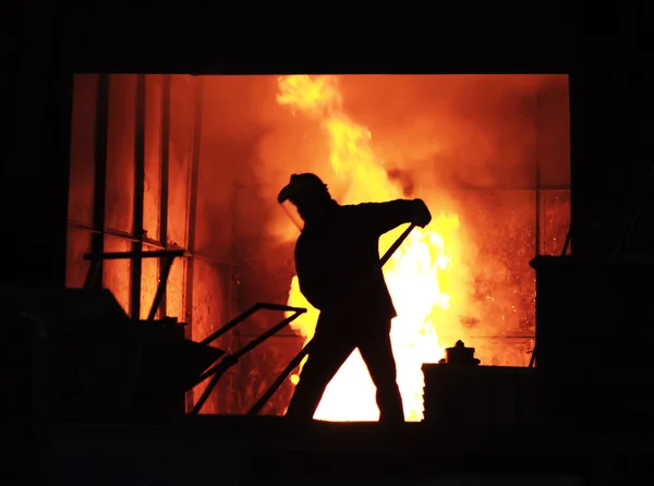 L'uomo sta lavorando nel ferro fuso spruzzando - Stock Image — Foto Stock