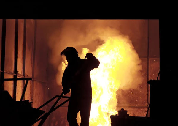 El hombre está trabajando en la salpicadura de hierro fundido - Stock Image — Foto de Stock