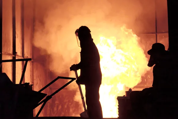 El hombre está trabajando en la salpicadura de hierro fundido - Stock Image — Foto de Stock