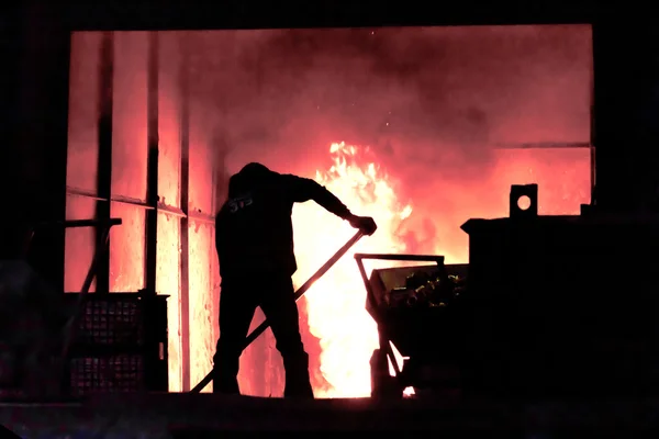 El hombre está trabajando en la salpicadura de hierro fundido - Stock Image — Foto de Stock