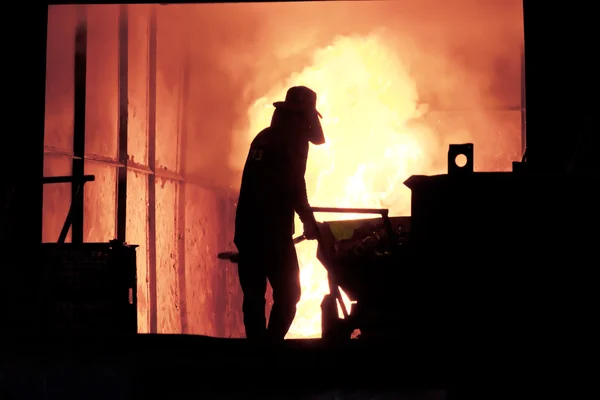 El hombre está trabajando en la salpicadura de hierro fundido - Stock Image — Foto de Stock