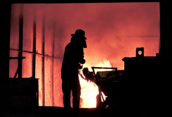 L'uomo sta lavorando nel ferro fuso spruzzando - Stock Image — Foto Stock