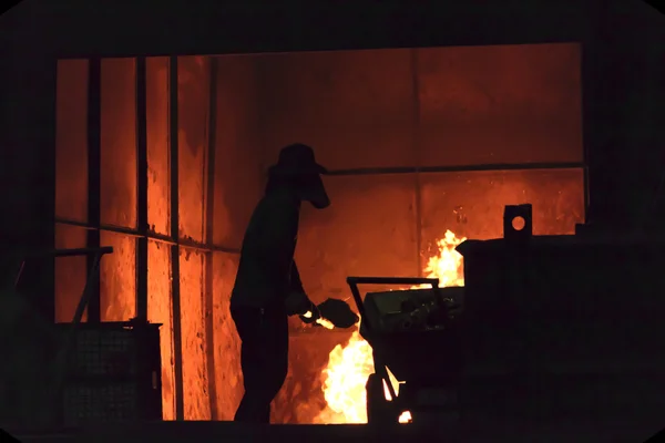 El hombre está trabajando en la salpicadura de hierro fundido - Stock Image — Foto de Stock