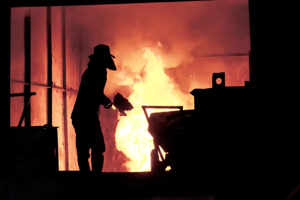 L'uomo sta lavorando nel ferro fuso spruzzando - Stock Image — Foto Stock