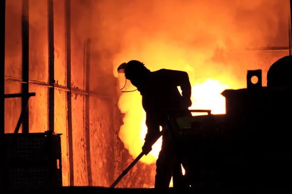 L'uomo sta lavorando nel ferro fuso spruzzando - Stock Image Foto Stock